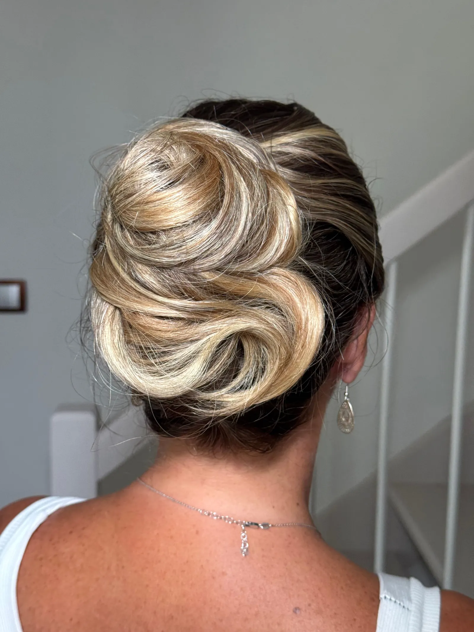 Chignon travaillé en volutes sur cheveux blonds méchés, vu de dos